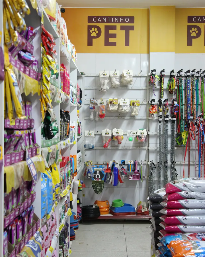 Cantinho Pet do Kumamoto, com placa amarela, coleiras, brinquedos e sacos de ração