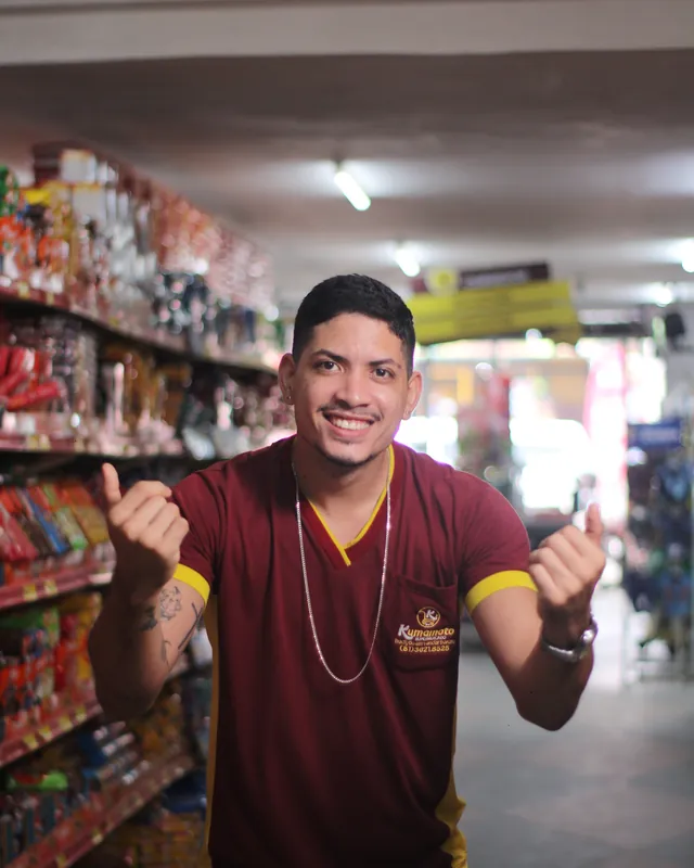 Colaborador do Kumamoto fazendo sinal de positivo no corredor de mercearia