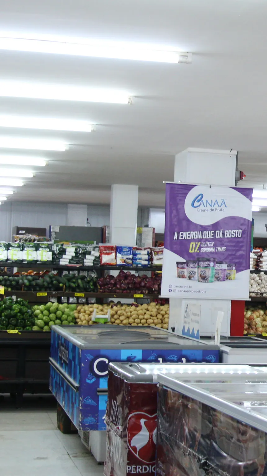 Salão do Kumamoto com ilhas de oferta, hortifruti ao fundo e clientes fazendo compras